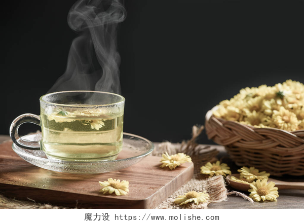 木板上的茶杯和菊花菊花茶与热蒸汽和菊花在篮子里的黑色背景。健康的饮料狂怒。草药和医疗概念.